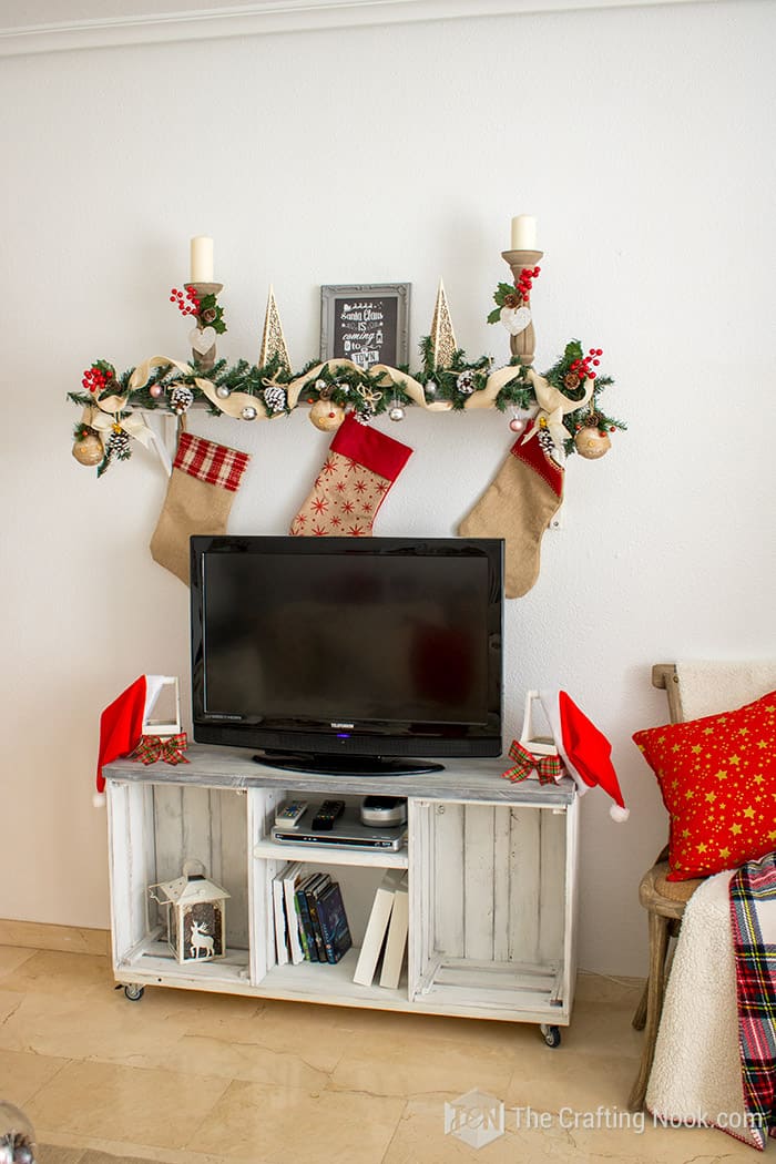 view of Tv console, with a wooden candle holder on each side decorated with a plaid bow and a Santa hat.