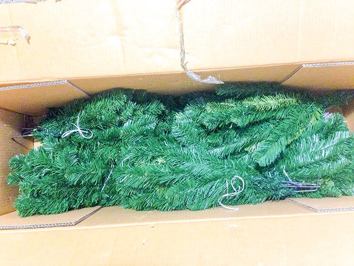 placing the parts of the artificial pine inside its cardboard box in an orderly manner