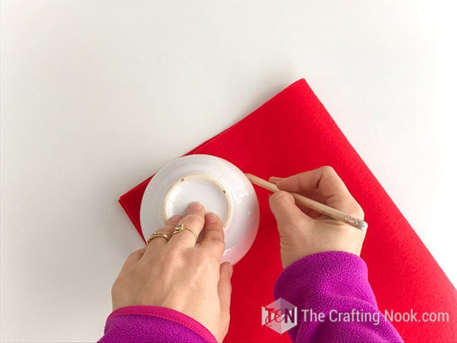 using a big cup to trace a circle onto the red felt