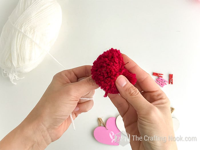 the threaded needle inserted through a red pom pom