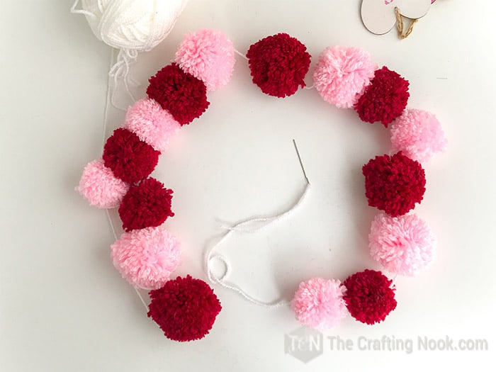 All the red and pink pom poms alternating on the yarn string.