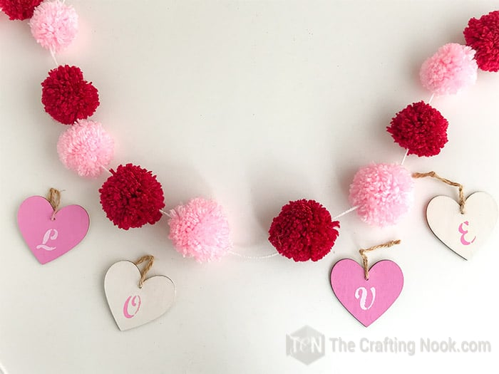 The Pom Pom Garland with evenly spread out pom poms and the wooden hearts ready to be assembled.