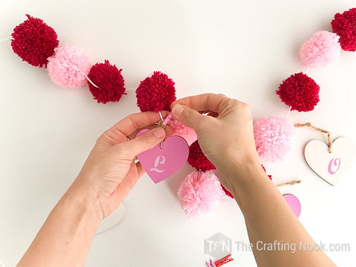 securing the wooden heart to the garland with the clothespin.