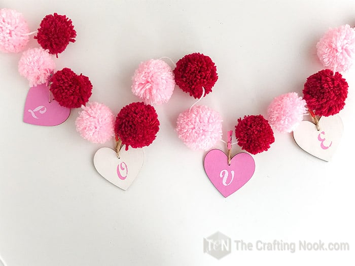 The Pom Pom Garland finished with all 4 wooden hearts reading L O V E hanging.