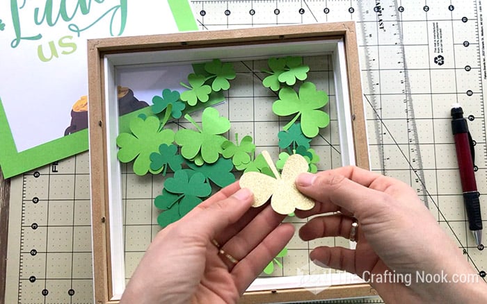 Filling up the St. Patrick's Day Shadow Box frame with shamrocks and a golden clover