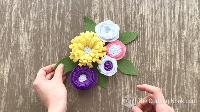 an small arrangement of different felt flowers diy and green leaves