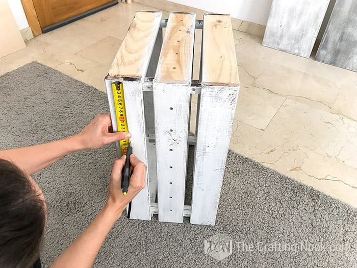 measuring the height of the center shelf on one crate