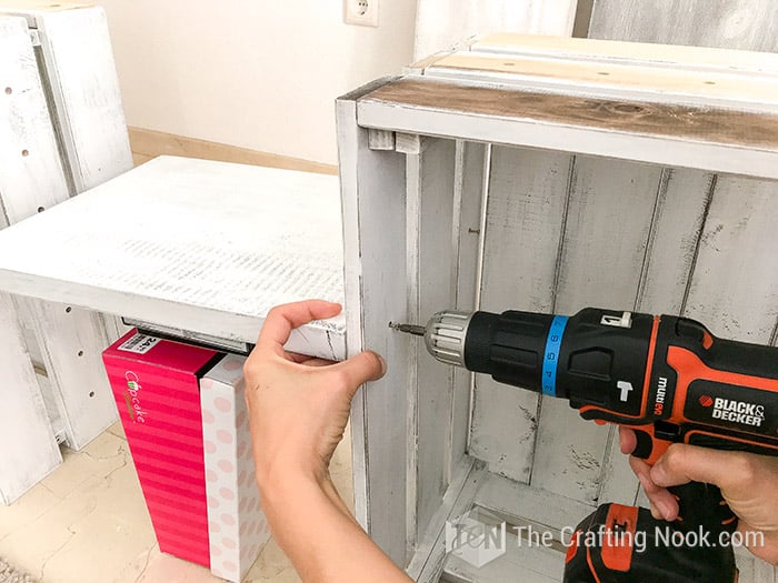 drilling the screws to the shelf board on one crate