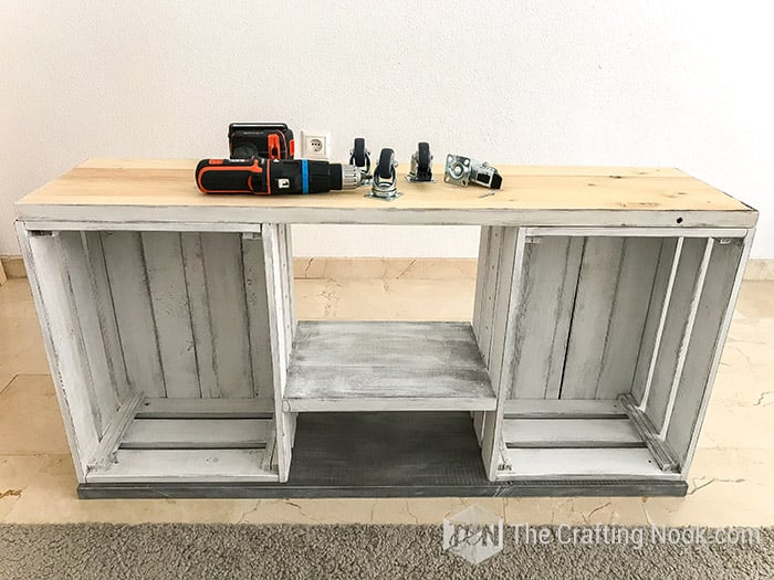 the rustic tv console table turned upside down with drill and wheels on it