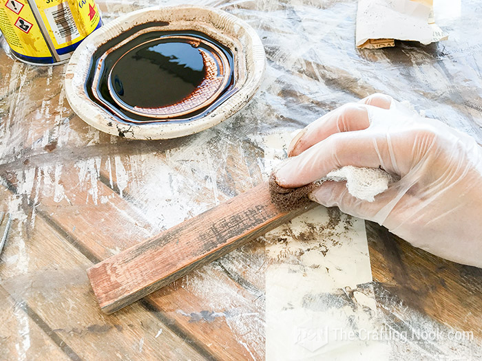 Applying dark stain to the already painted and sanded piece of wood