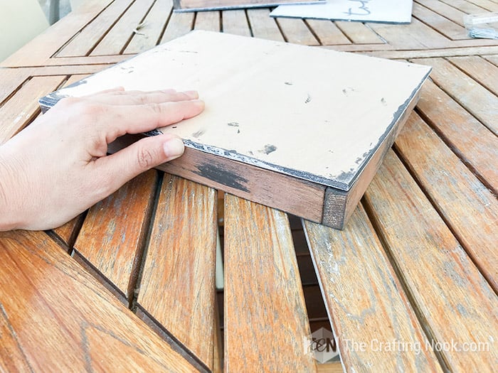 Placing face down the piece of wood with the phrase already painted on the frame
