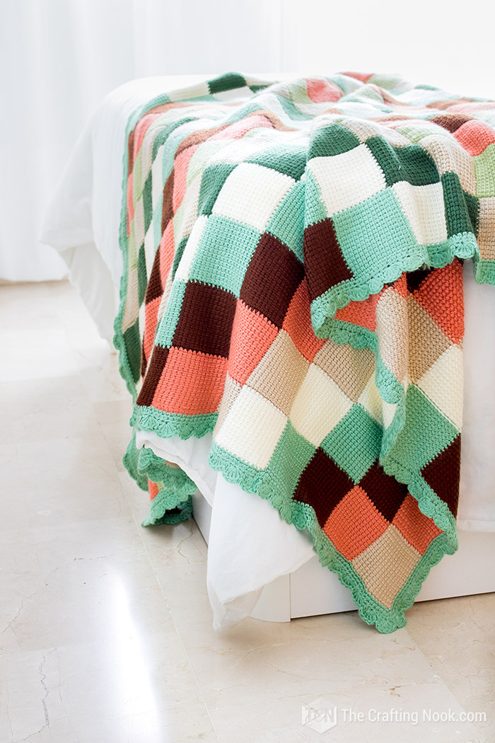 closer view of knitted blanket over the corner of the bed