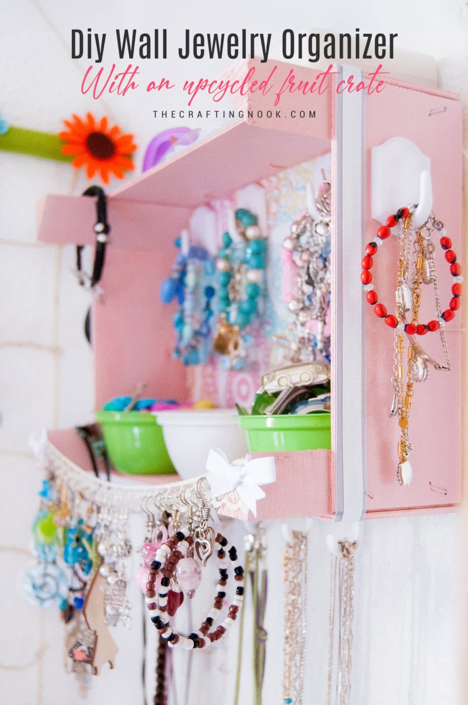 DIY Wall Jewelry Organizer With An Upcycled Fruit Cratefilled with jewelry and hanging on the wall. Feature image with title text overlay