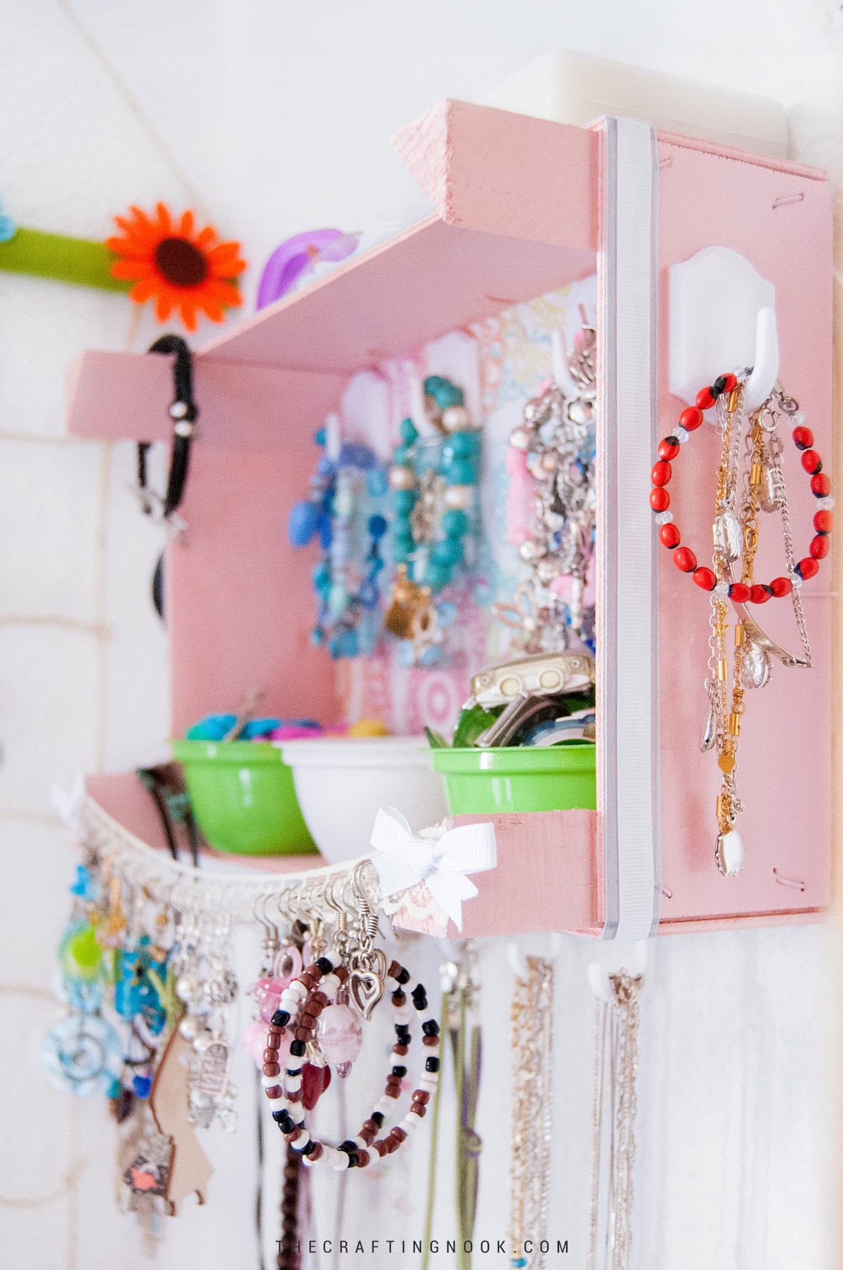 DIY Wall Jewelry Organizer With An Upcycled Fruit Cratefilled with jewelry and hanging on the wall. Feature image