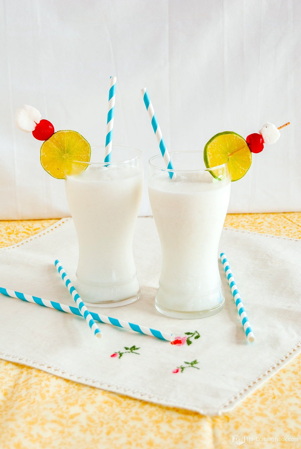 Front view of the two cups of Frozen coconut limeade Drink with Malibu decorated with cute straws and lime slices