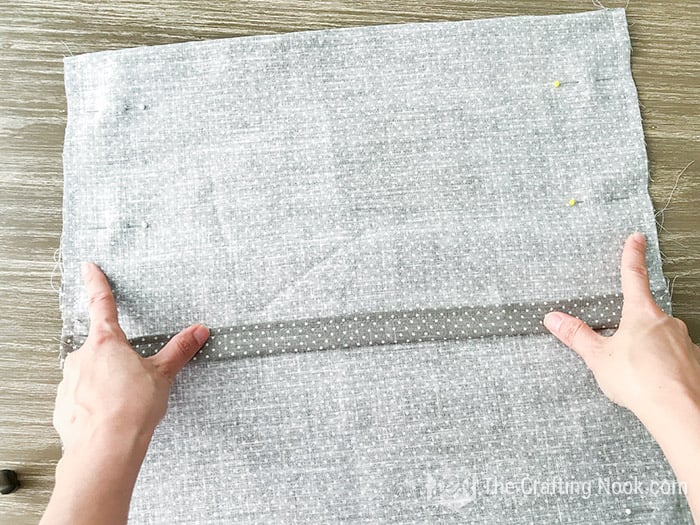 top view of hands showing back view of the fabric with pins lining the edges