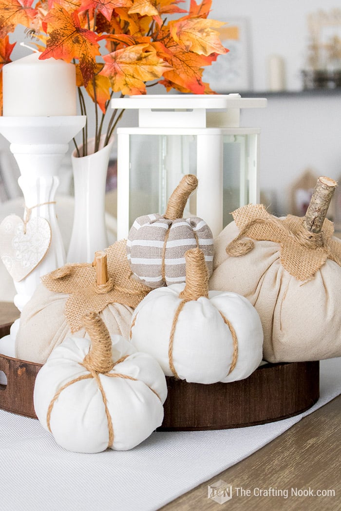 A beautiful fall centerpiece with fabric pumpkins diy, a lantern, and fall foliage.