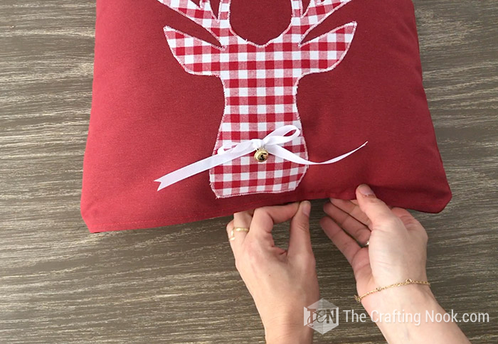 Finishing inserting a through pillow inside one of the Reindeer Applique Plaid Christmas Pillows