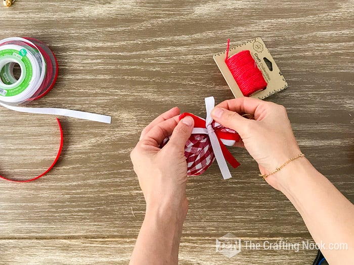 adjusting the red and white bow at the top of the lined ball