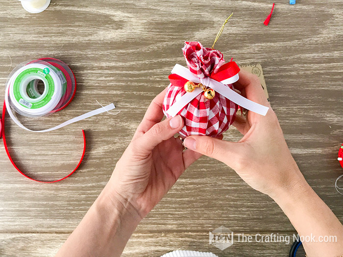 showing the ball already made with the red and white bow and jingle bells