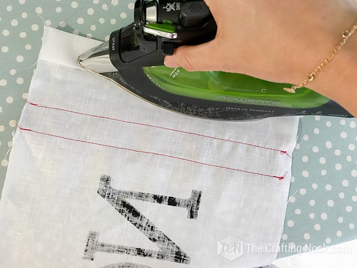 ironing the fold of the fabric along the edge
