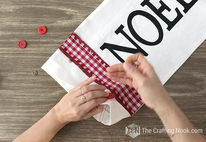 Sewing the buttons to the Farmhouse Christmas Pillow