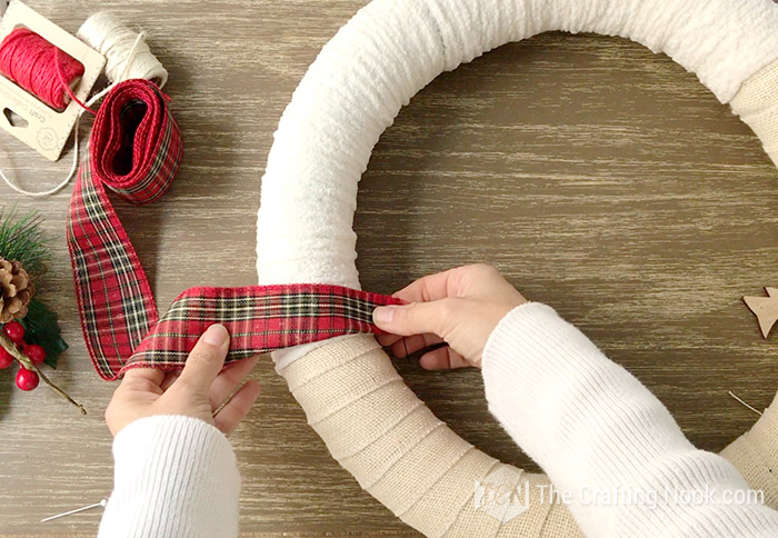 wrapping the wreath with the Buffalo Plaid ribbon overlapping the burlap