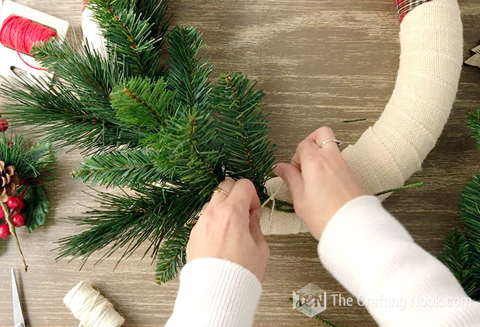 tying the branches of the tree to the base of the wreath with a thread
