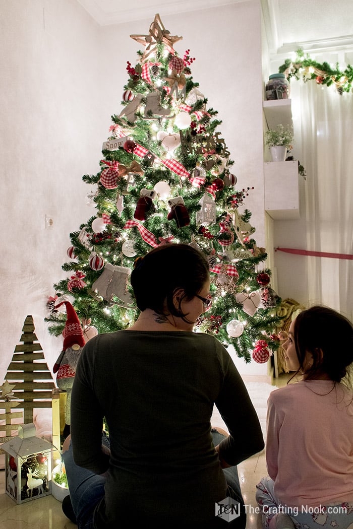 me and my daughter sitting in front of the christmas tree with the lights on
