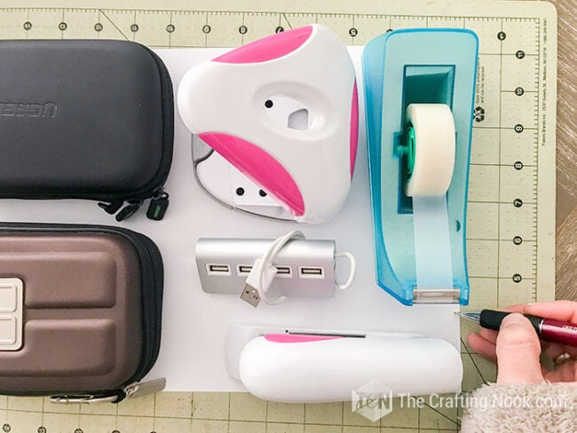 Tracing the edge of a tape dispenser on the cardstock template while planning the drawer compartments.