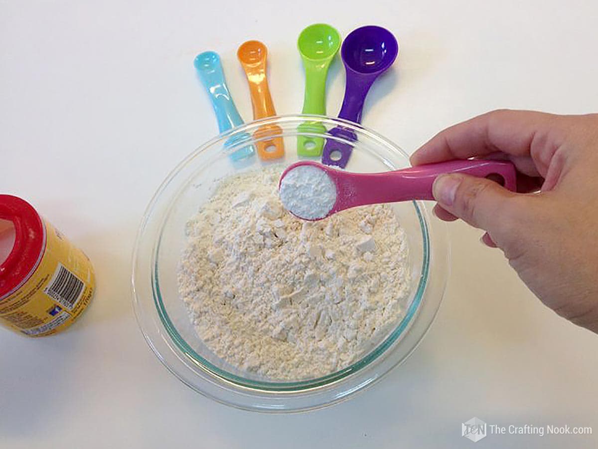 image of glass bowl with wheat flour and measuring spoons
