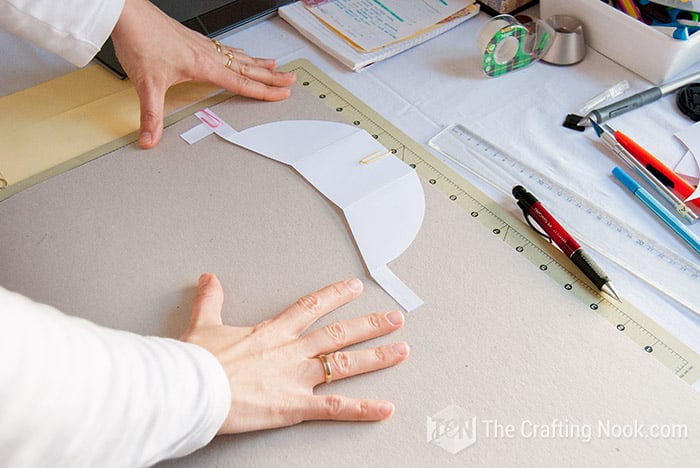 placing the pattern on the cardboard to cut it with the shape