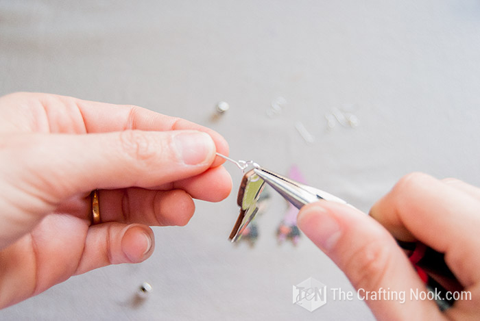 image of hands holding eye pin and using pliers the wooden charm
