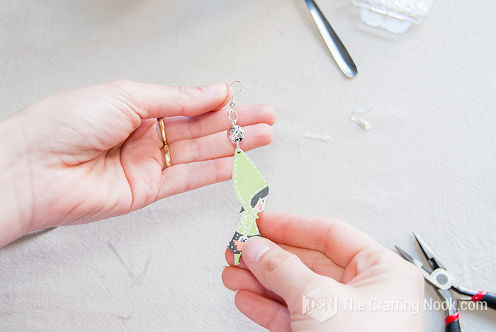 showing the wooden earring between the hands
