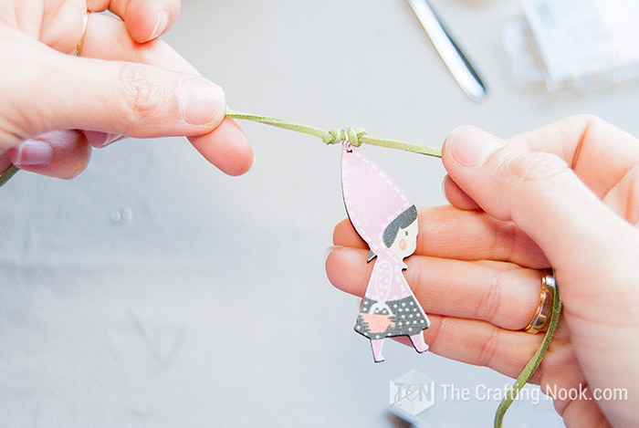 showing how the wooden pendant should be placed between the knots of the cord
