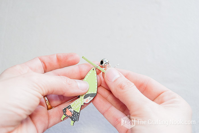 inserting a strip of cord between the ring and the spacer of the wooden earring
