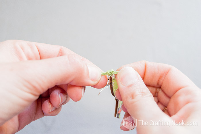 making a simple knot to the strip of cord between the ring and the spacer of the wooden earring
