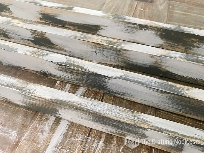 rustic wood sign frame boards painted with rough strokes of white paint over grey already dry