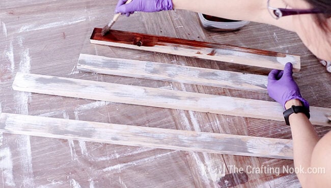 applying a coat of stain over the wood slats