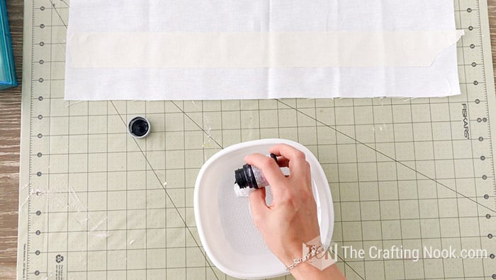 mixing black and white paint in a plastic dish to prepare the gray base