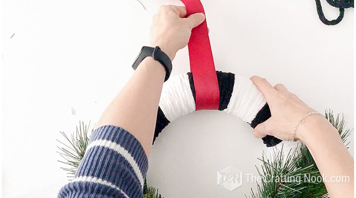 placing a thick red ribbon on top of wreath