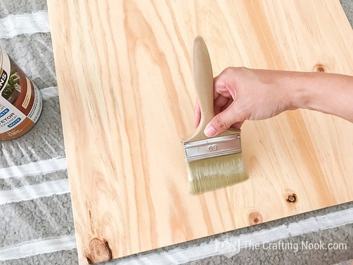 image of a piece of wood and on it, the process of painting with a broad brush