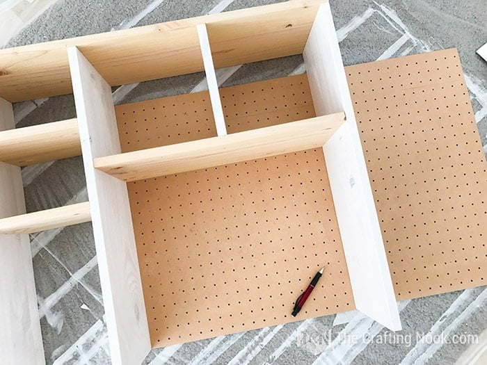 measuring the pegboard next to the shelving structure