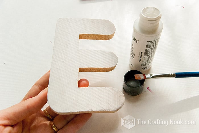 showing the painted the E letter in white in hand