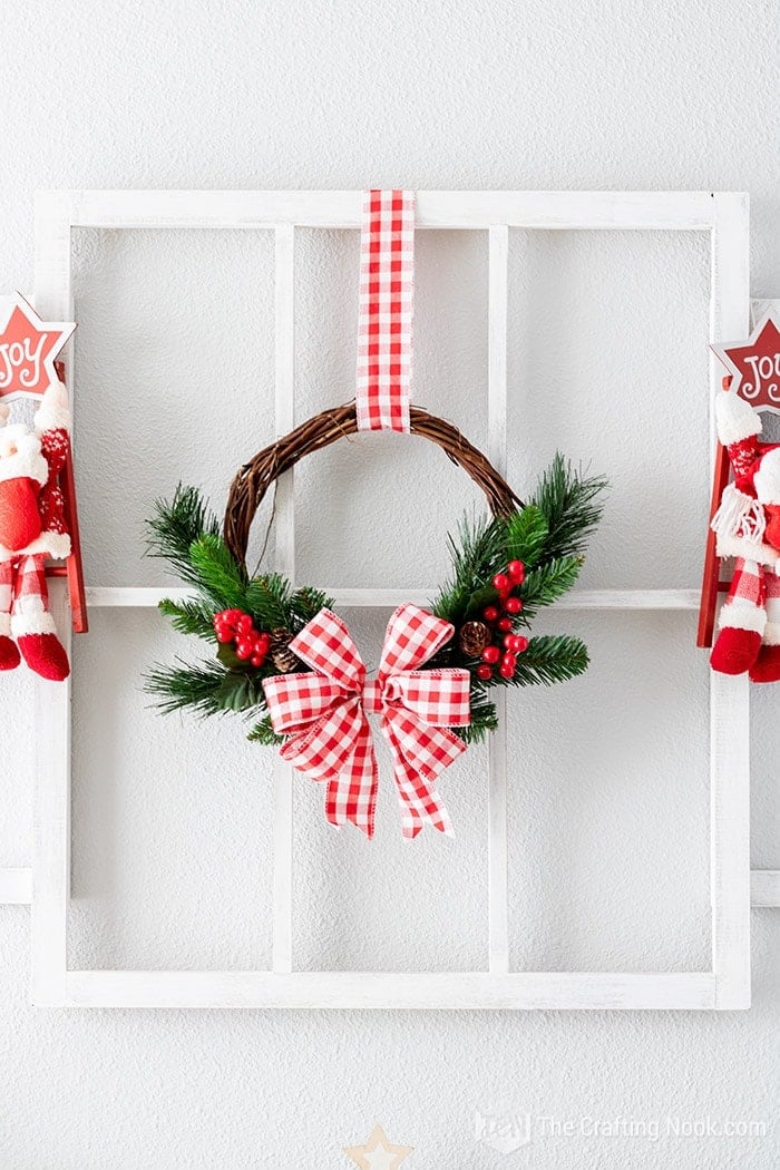 DIY Rustic Christmas Wreath in Red and White Hanging on a window frame with ornaments around