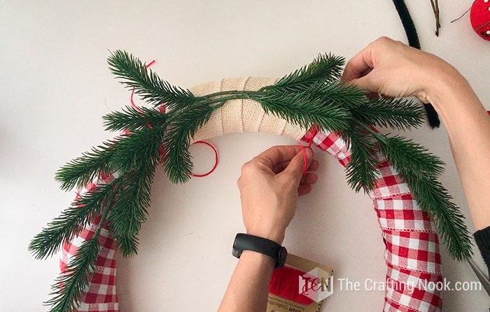 Securing each spring with a strip of twine tied on the back of wreath