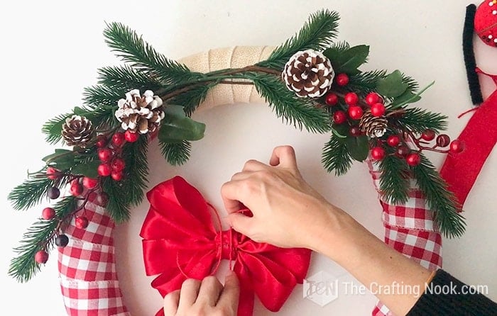 view of the wreath and hands making a red bow