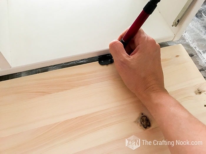 closer view of hand tracing the hinges holes on the door with pencil