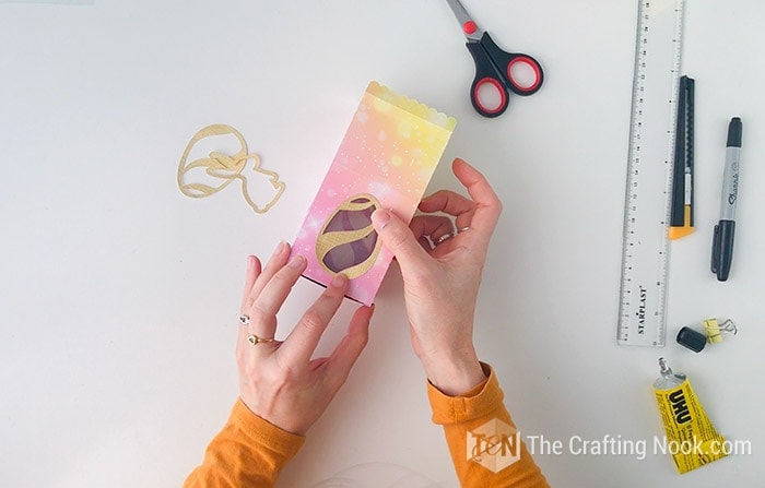 Decorating the diy easter treat boxes with gold easter egg accents.