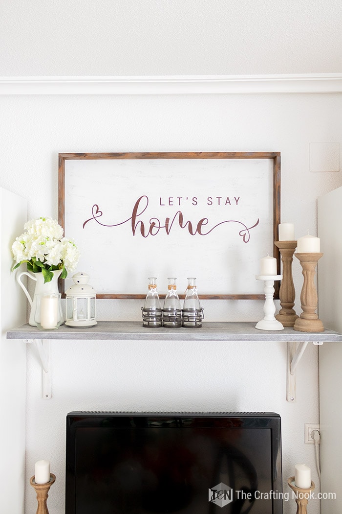 Front view of Rustic wood sign on the wall with Let's Stay Home sentiment.